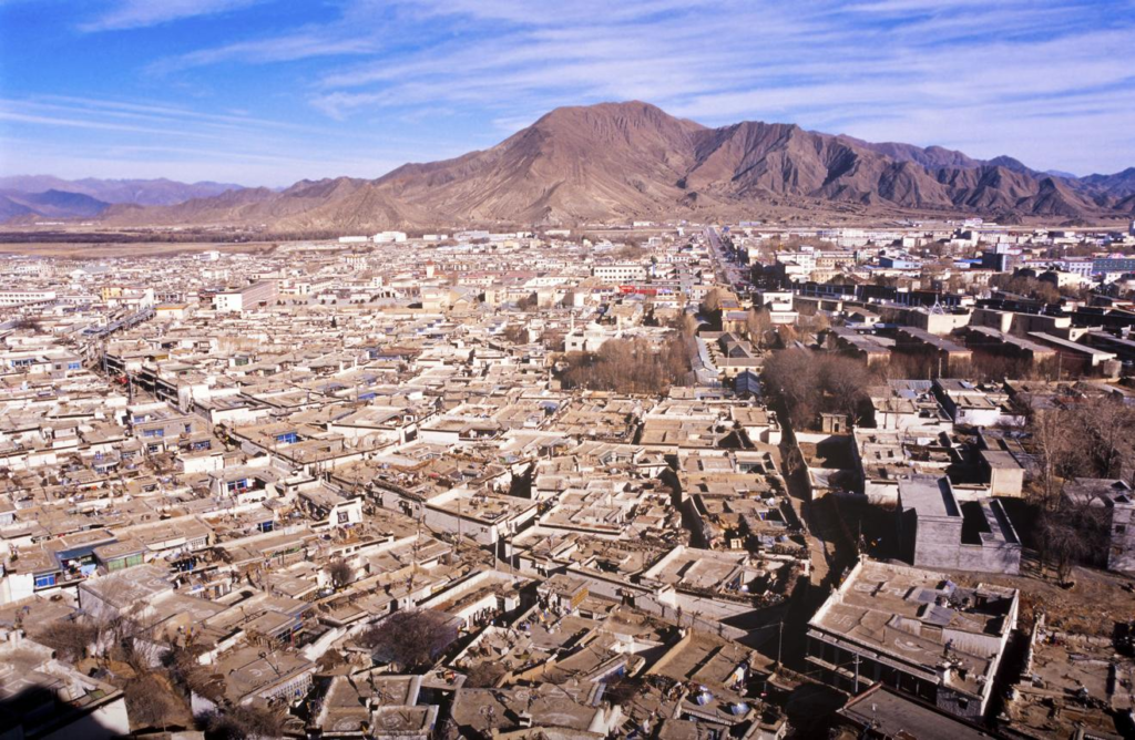 An aerial view of Shigatse showing the city nestled in the Tibetan plateau with Himalayan mountains in the background