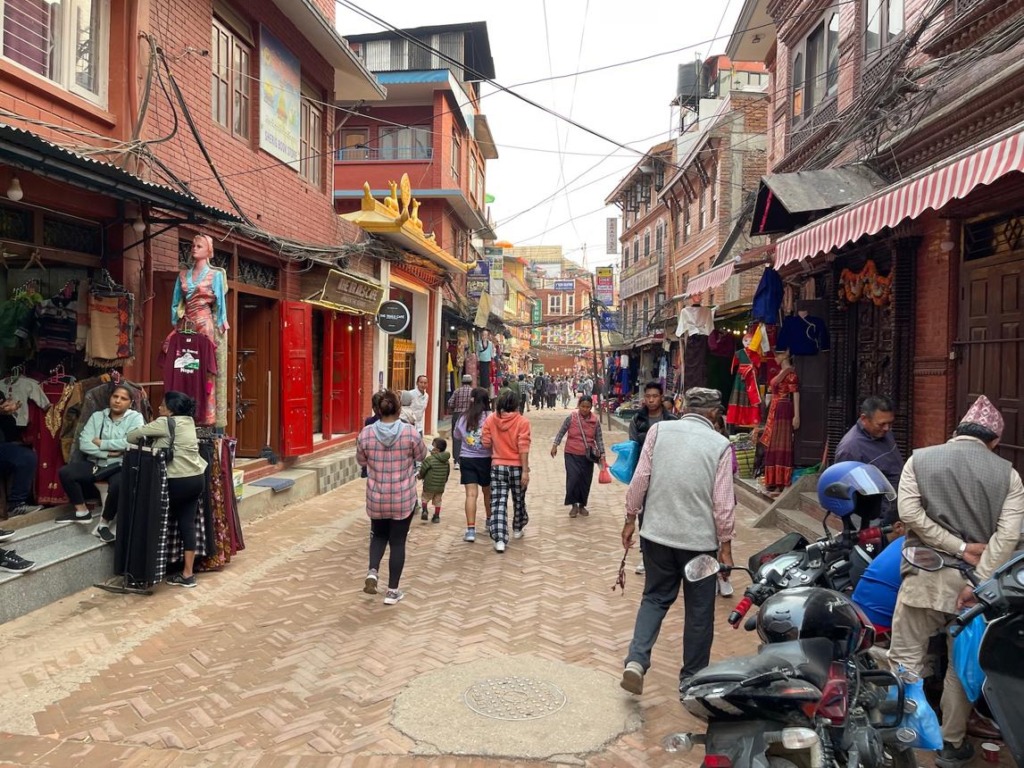 Visitors walking through bustling streets in Kathmandu with markets, shops, and traditional Nepali architecture.